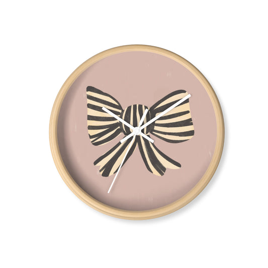 Round bamboo nursery wall clock with hand-painted striped black and cream bow on a muted pink background and white clock hands