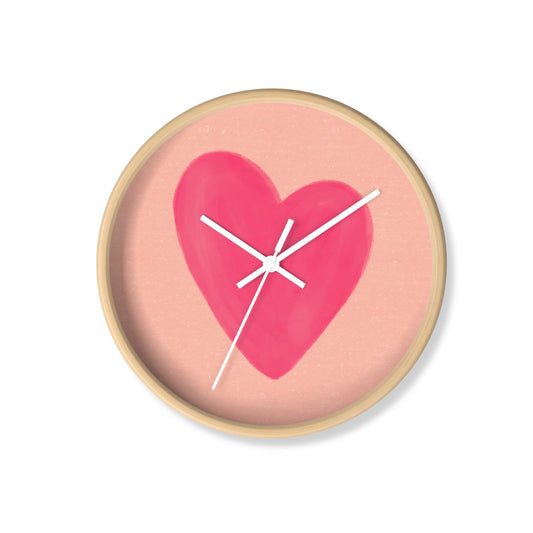 Round bamboo nursery wall clock with hand-painted pink heart on a peach background and white clock hands